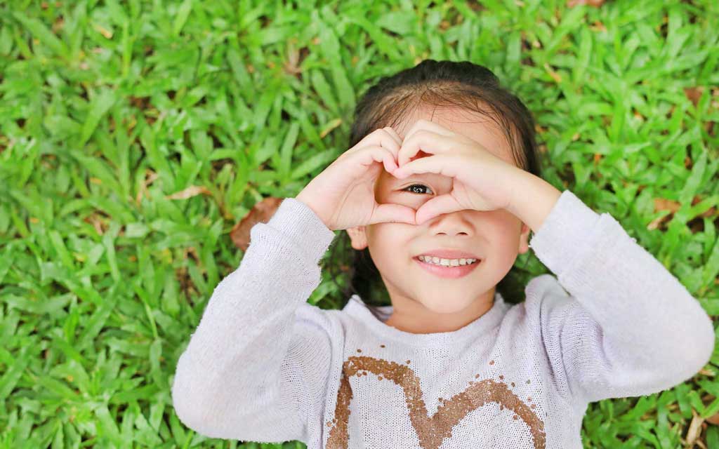 Girl lying in grass with heart